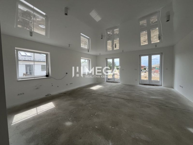 Ein geräumiges, helles Zimmer mit großen Fenstern in einem Einfamilienhaus.