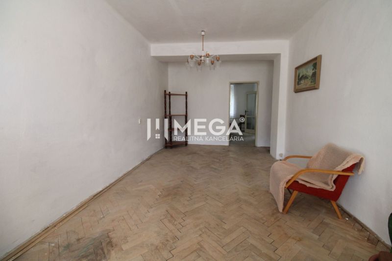 Wohnzimmer mit einem alten Sessel und einem Boden mit Holzdekor in einer 2-Zimmer-Wohnung.