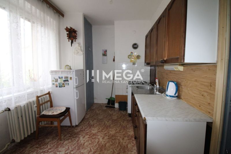 Küche in einer 2-Zimmer-Wohnung mit Kühlschrank, Holzboden, hellem Vorhang.