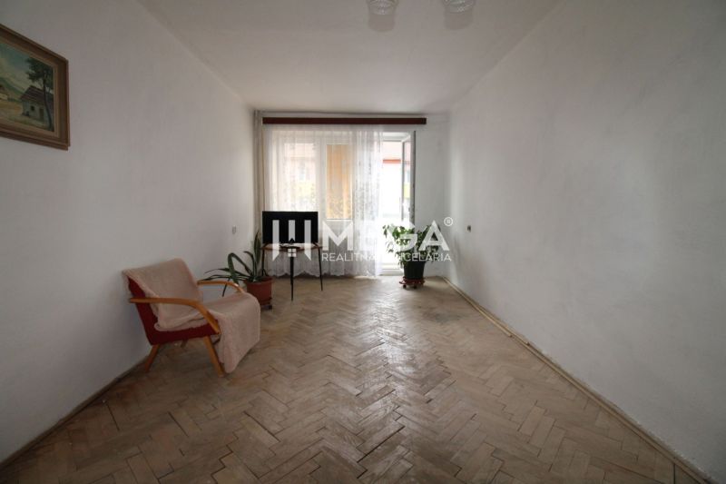 Wohnzimmer in einer Zweizimmerwohnung mit Holzboden und einfacher Einrichtung.