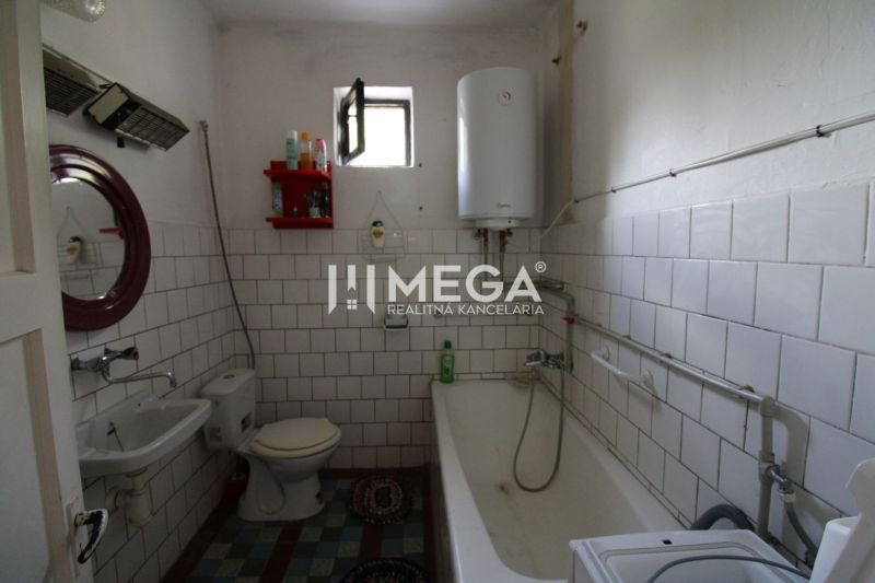 Badezimmer in einem Einfamilienhaus mit Badewanne, Waschbecken und einem an der Wand montierten Kessel.
