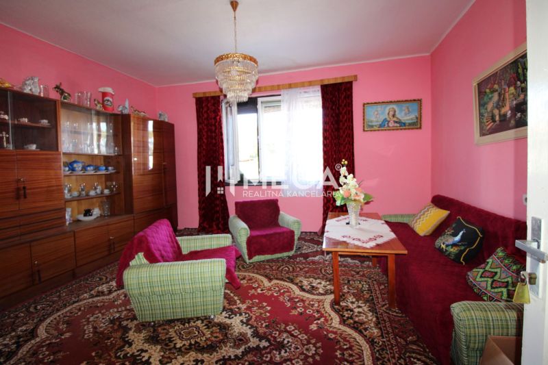 Wohnzimmer mit rosa Wänden, Sitzgarnitur, Vitrine und Kronleuchter in einem Einfamilienhaus.