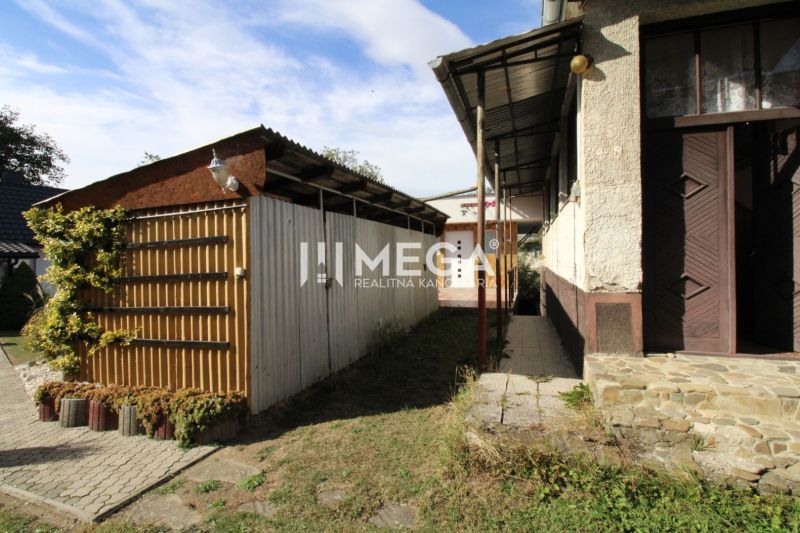 Ein Einfamilienhaus in Volica mit einem Blechunterstand im Hof und Kletterpflanzen.