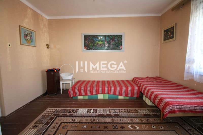 Ein Zimmer in einem Einfamilienhaus mit Teppichen, Betten und einem stehenden Ofen.