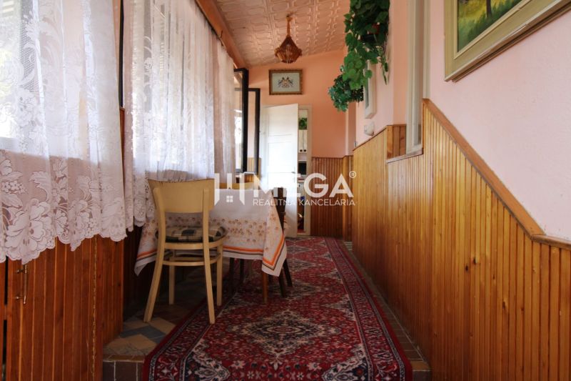 Ein Flur mit einem Teppichläufer, einem Tisch, Vorhängen und Holzvertäfelung in einem Einfamilienhaus.