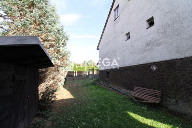 Garten bei einem Einfamilienhaus in der Volica-Straße in der Stadt Volica mit einer Bank und Nadelbäumen.