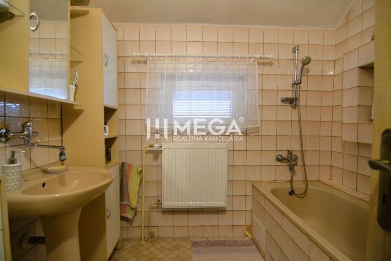 Badezimmer in einem Einfamilienhaus mit beigen Fliesen, einer Badewanne und einem Waschbecken.