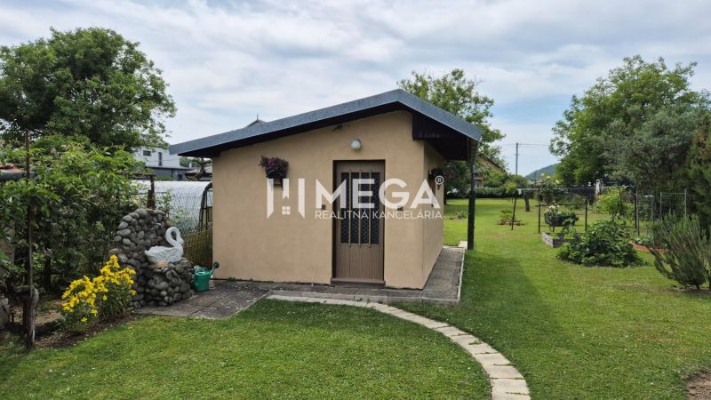 Ein Einfamilienhaus in Lackovce mit gepflegtem Rasen, Garten und einem kleineren Gebäude im Hintergrund.