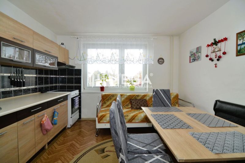Küche in einem Einfamilienhaus mit Küchenzeile und Esstisch, Boden mit Holzdekor.