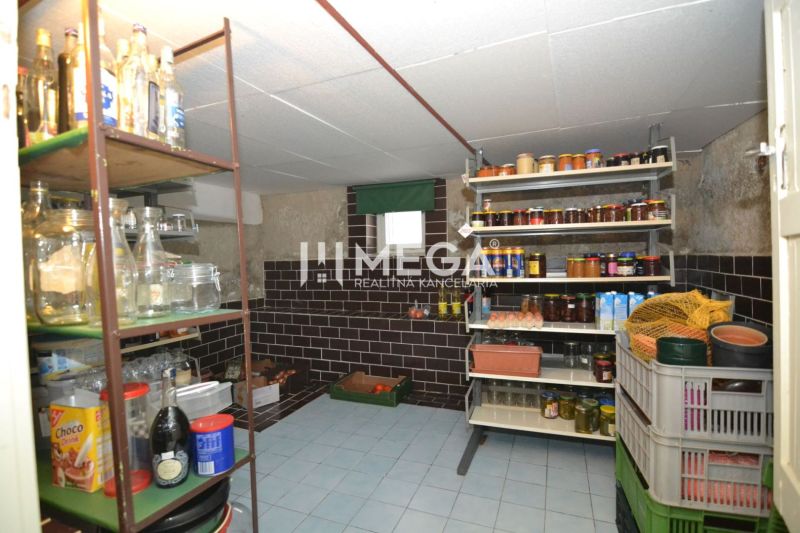 Speisekammer mit Regalen voller Einmachgläser in einem Einfamilienhaus, mit Steinen verkleidete Wände und Fliesenboden.