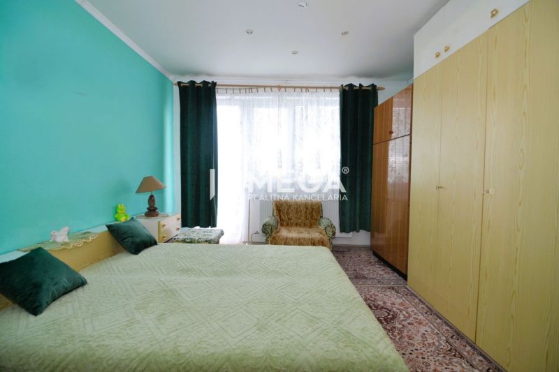 Ein Schlafzimmer in einem Einfamilienhaus mit einer türkisfarbenen Wand, einem großen Bett und Schränken.