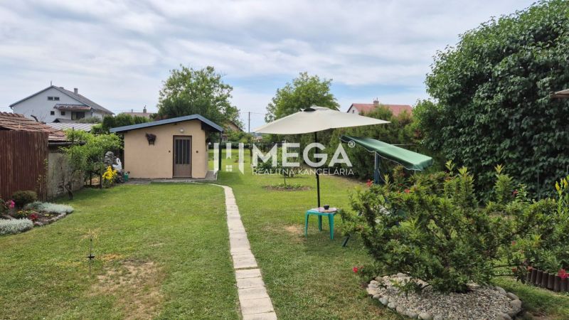 Der Garten des Einfamilienhauses in Lackovce mit Rasen, Sitzbereich und einem kleinen Bauwerk.