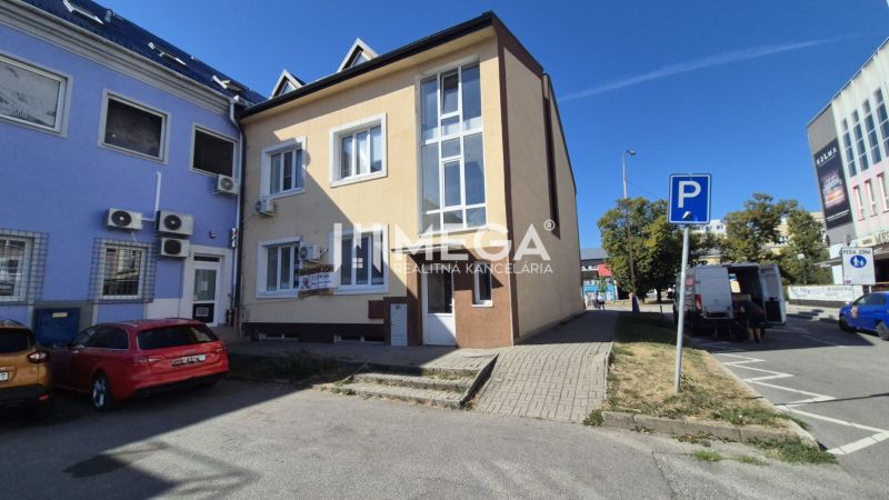 Ein Gebäude mit Geschäftsräumen am Freiheitsplatz in Humenné, vor dem sich Parkplätze befinden.