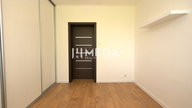 Ein Zimmer in einem Einfamilienhaus mit einem Boden in Holzoptik und einem Schrank.
