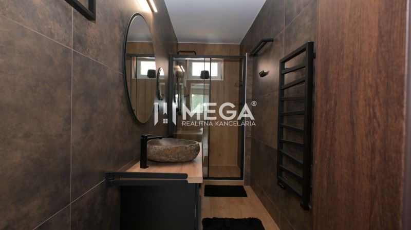 Ein Badezimmer in einem Einfamilienhaus mit Spiegel, Waschbecken und dunklen Wänden.