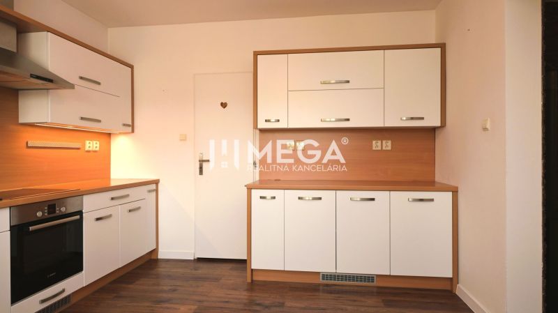 Küche in einem Einfamilienhaus mit weißen Schränken, Geräten und einem Boden in Holzoptik.