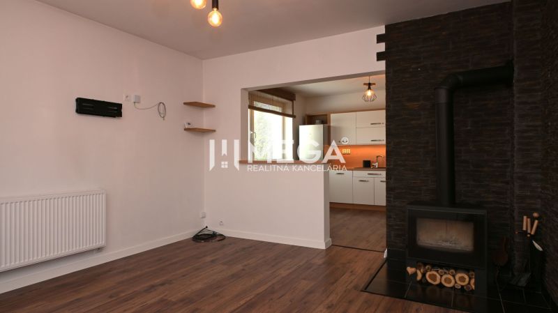 Innenraum eines Einfamilienhauses mit Kamin, Holzboden und Blick in die Küche.