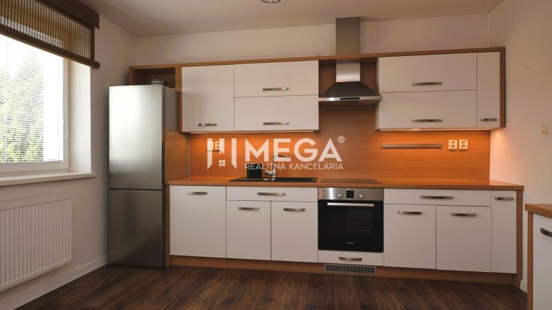 Eine Küche in einem Einfamilienhaus mit weißen Schränken und einem Boden in Holzoptik.