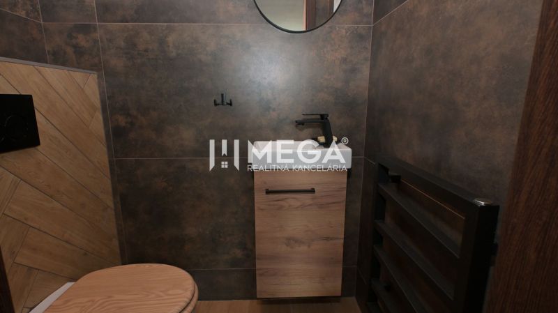 Ein Badezimmer in einem Einfamilienhaus mit braunen Fliesen und einem Boden in Holzoptik.