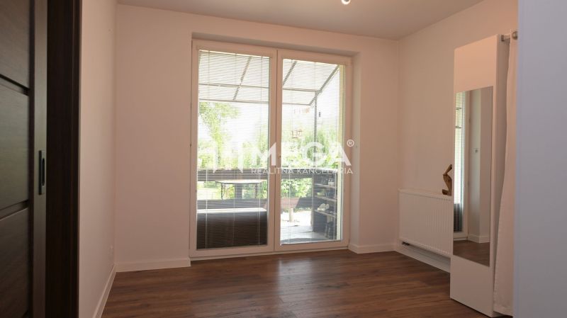 Ein Zimmer mit Holzboden, großes Fenster, Heizkörper, Spiegel. Ein Einfamilienhaus.