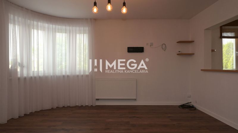 Innenraum eines Einfamilienhauses mit Holzboden, Vorhängen und Hängelampen.