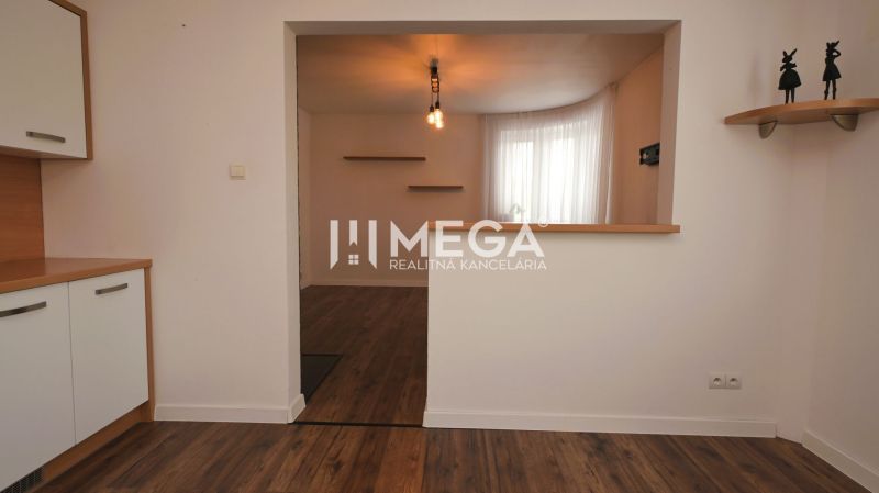 Innenraum eines Einfamilienhauses mit Holzboden, Küchenzeile und Regalen.