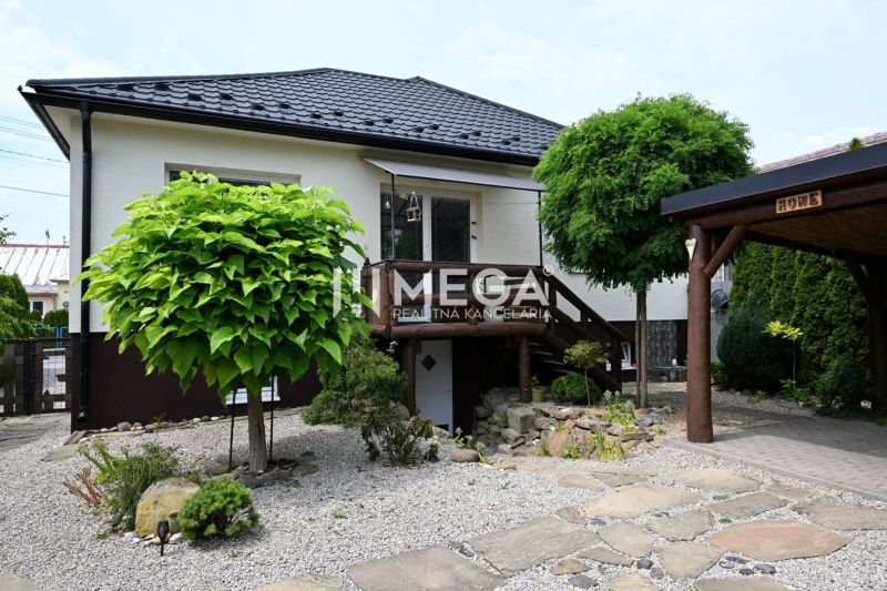 Ein Einfamilienhaus in Udavské mit einem gepflegten Garten und einer gepflasterten Zufahrtsstraße.