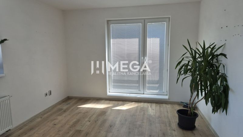 Ein Büro mit einer Pflanze, einem Holzboden und Balkontüren mit Jalousien.