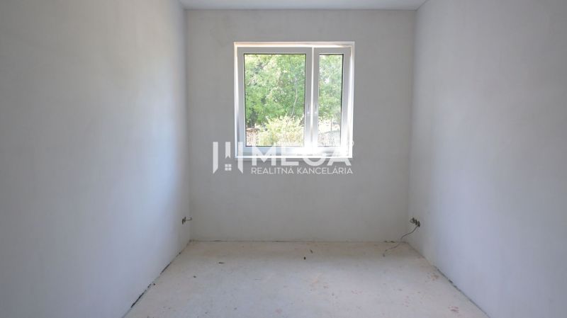 Ein leerer Raum in einem Einfamilienhaus mit weißen Wänden und einem Fenster.