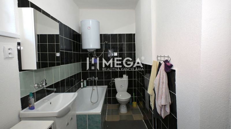 Badezimmer in einem Einfamilienhaus mit Badewanne, Waschbecken und Kessel, schwarz-weiße Fliesen.