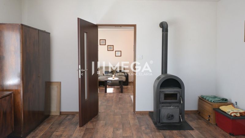 In einem Einfamilienhaus gibt es einen Ofen, Schränke, Türen und einen Boden mit Holzdekor.