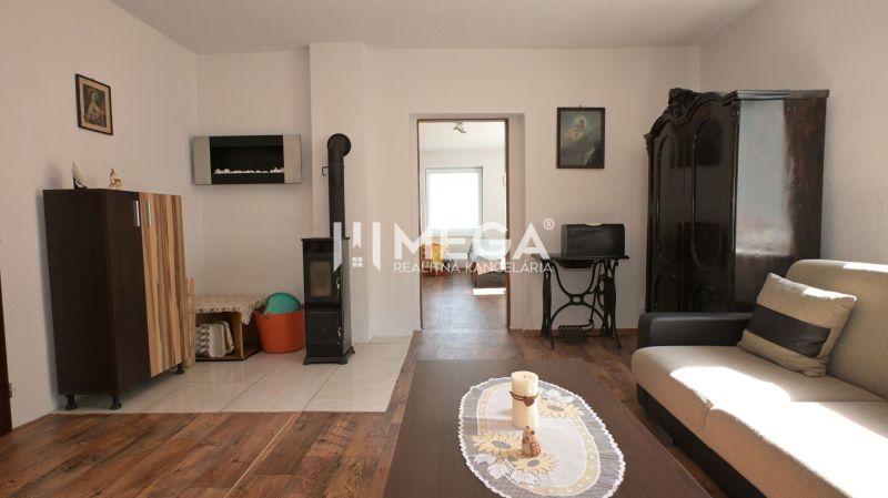 Wohnzimmer in einem Einfamilienhaus mit Kacheln und einem Boden in Holzoptik.