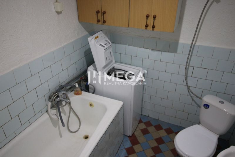 Ein Badezimmer im Einfamilienhaus mit Badewanne, Waschmaschine und Toilette, gefliest.