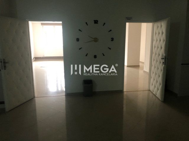 Innenraum eines Gebäudes mit auffälliger Uhr an der Wand und offenen Türen.