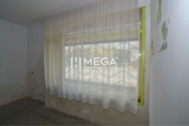 Geschäftsräume mit Vorhängen, einem Gitter am Fenster und abgenutzten Wänden.