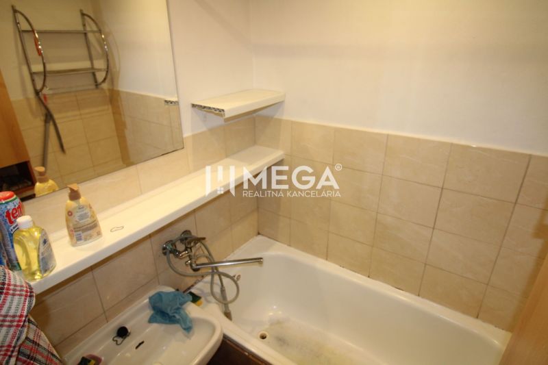 Badezimmer mit Fliesen, Badewanne und Waschbecken in einer 3-Zimmer-Wohnung.