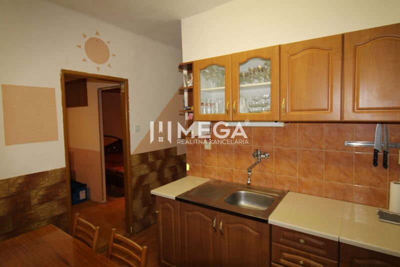 Küche mit Holzschränken und orangefarbenen Fliesen in einer 3-Zimmer-Wohnung.