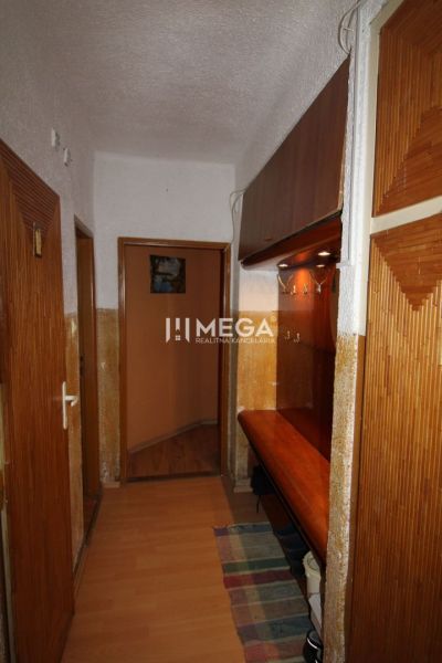 Der Flur in der 3-Zimmer-Wohnung mit einem Boden in Holzoptik und Holzmöbeln.
