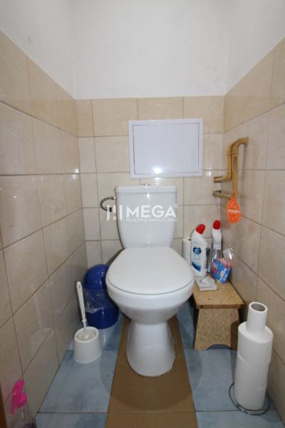 Toilette mit Fliesen in einer 3-Zimmer-Wohnung, ergänzt mit Reinigungsmitteln und Toilettenpapier.