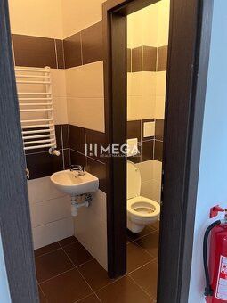 Toilette in Geschäftsräumen mit braunen und weißen Fliesen.