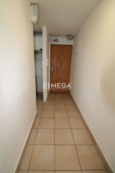 Ein schmaler Flur mit Fliesen und Holztüren in einer 3-Zimmer-Wohnung.