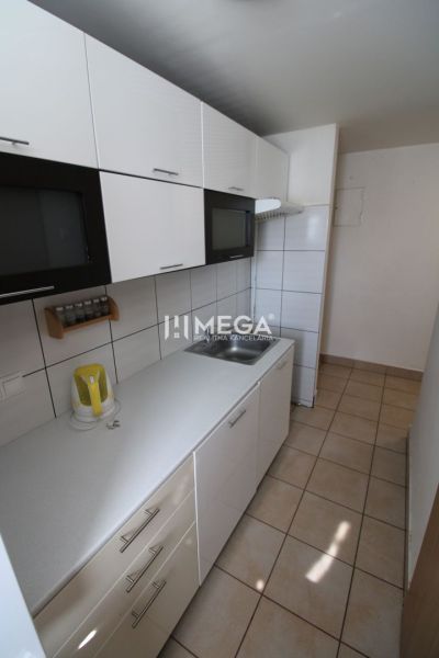 Küche in einer 3-Zimmer-Wohnung mit weißen Schränken und Fliesenboden.