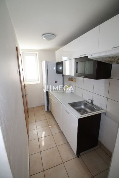 Küche in einer 3-Zimmer-Wohnung mit weißen Schränken und Keramikfliesen.