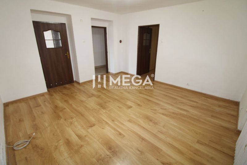 Ein leerer Raum mit weißen Wänden und einem Boden in Holzoptik in einer 3-Zimmer-Wohnung.
