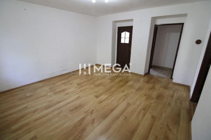 Ein Zimmer in einer 3-Zimmer-Wohnung mit einem Boden in Holzoptik und weißen Wänden.