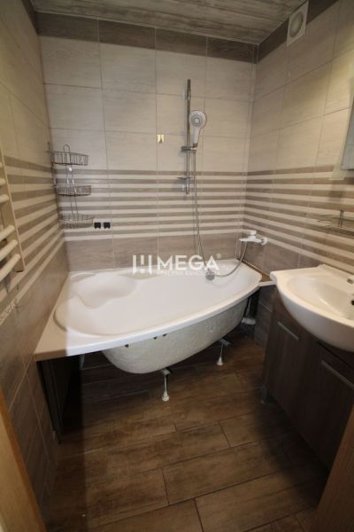 Badezimmer mit Badewanne und Waschbecken in einer 3-Zimmer-Wohnung. Boden mit Holzdekor.