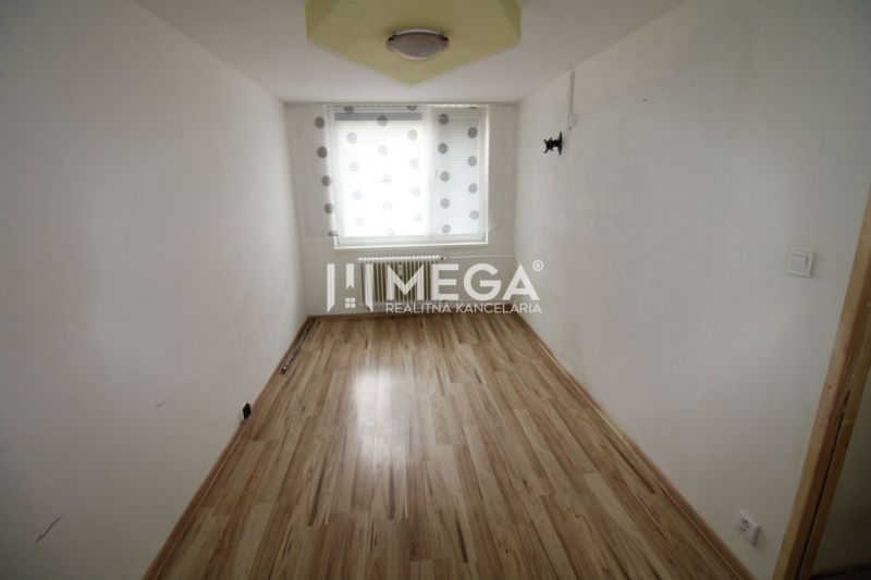 Ein schmaler Raum mit einem Fenster und einem Boden in Holzoptik in einer 3-Zimmer-Wohnung.
