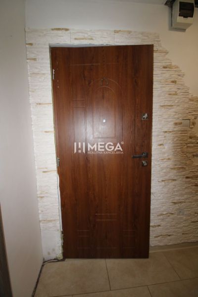 Eingangstür aus Holz in einer 3-Zimmer-Wohnung mit einer Verkleidung aus hellem Stein.