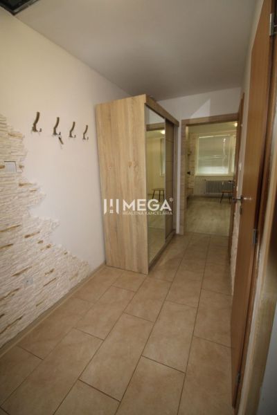 Flur einer 3-Zimmer-Wohnung mit Fliesenboden, Spiegelschrank und Wand mit Steinverkleidung.