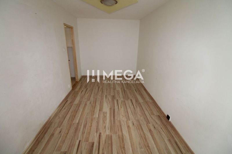 Ein Zimmer in einer 3-Zimmer-Wohnung mit einem Boden in Holzoptik und weißen Wänden.